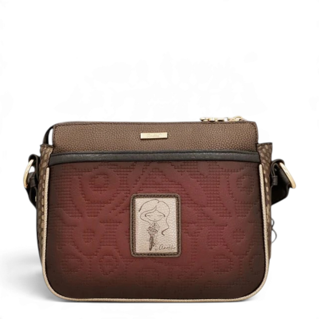 Anekke Core crossbody bag in bordeaux and brown with embroidered floral patterns, gold metal accents, and wide strap.