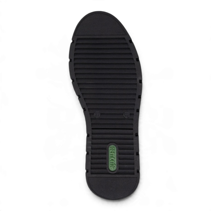 Black textured rubber outsole of a Remonte shoe with a green brand logo, showing a slip-resistant tread pattern.