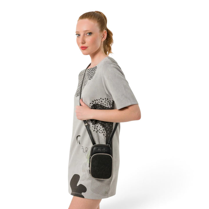 Model wearing a black Anekke crossbody bag with an adjustable strap, featuring a compact design and zippered closure.
