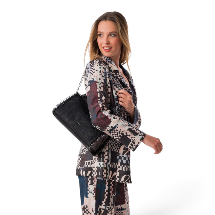 ada-shoes.ro Anekke Iron shoulder bag in black with metallic chain detail worn by a woman in a patterned suit