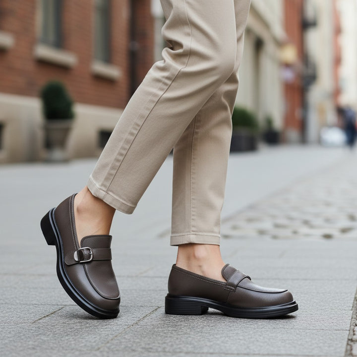 ada-shoes.ro Anna Viotti brown leather casual loafers with a side buckle detail worn with beige trousers on a city street