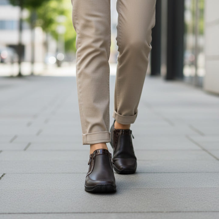 ada-shoes.ro Rieker dark brown casual ankle boots with side zippers worn with beige trousers on a city sidewalk
