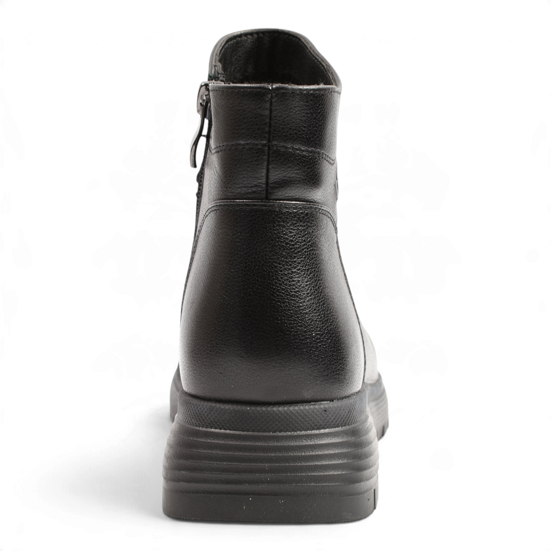 Back view of black leather Anna Viotti ankle boots with a thick, lugged rubber sole and side zipper detail.