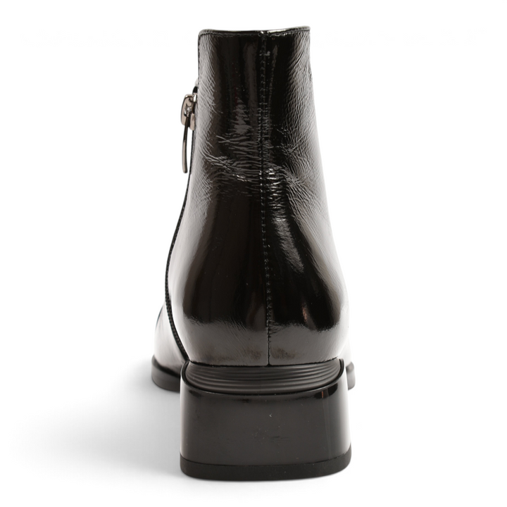 Back view of black patent leather Epica ankle boots with a low block heel and side zipper closure.
