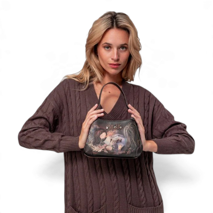 Woman holding an Anekke Dreamverse crossbody bag with artistic illustration, embroidery, and metallic logo details.