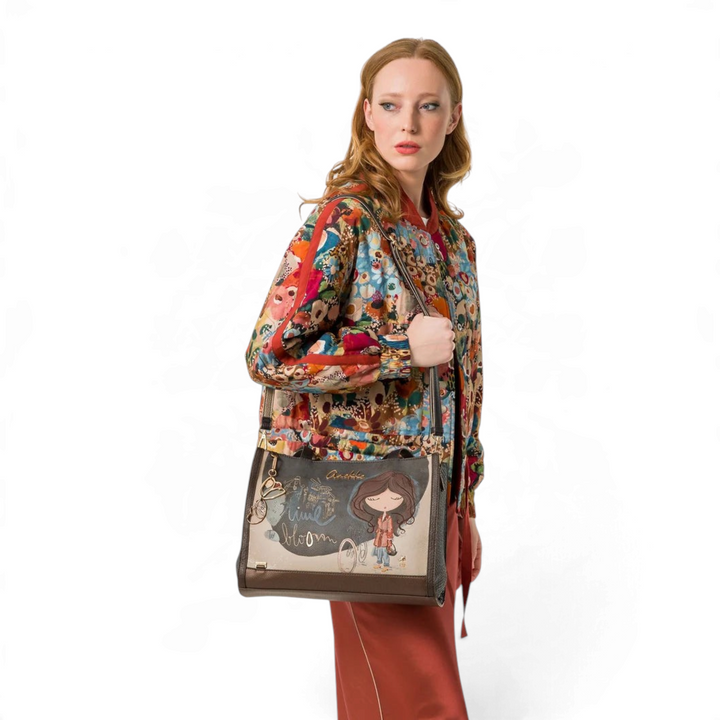 Model wearing an Anekke Bloom shopper bag in beige and brown faux leather with artistic print and gold metal details