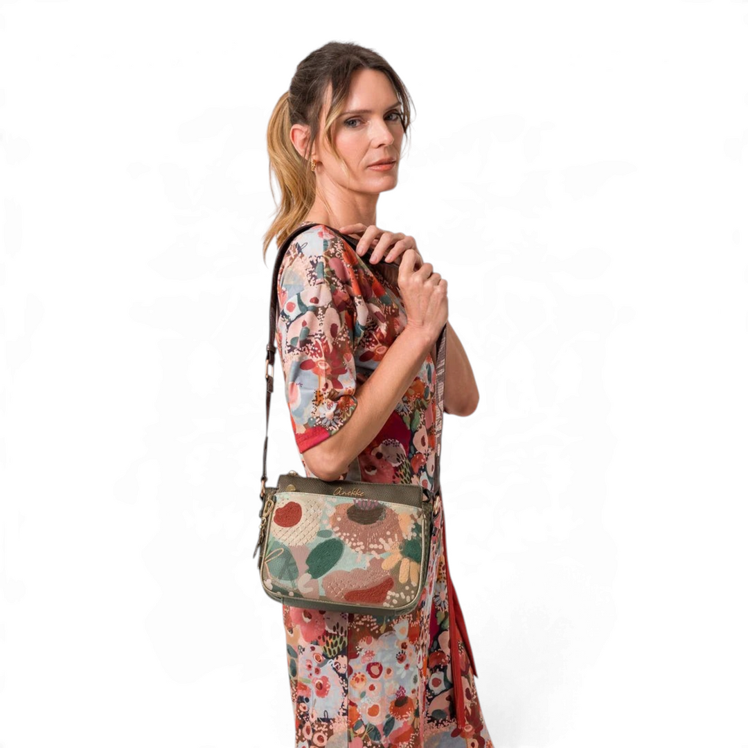 Woman wearing an Anekke Core crossbody bag with floral embroidery, metallic details, and a wide jacquard strap.