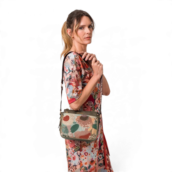 Woman wearing an Anekke Core crossbody bag with floral embroidery, metallic details, and a wide jacquard strap.