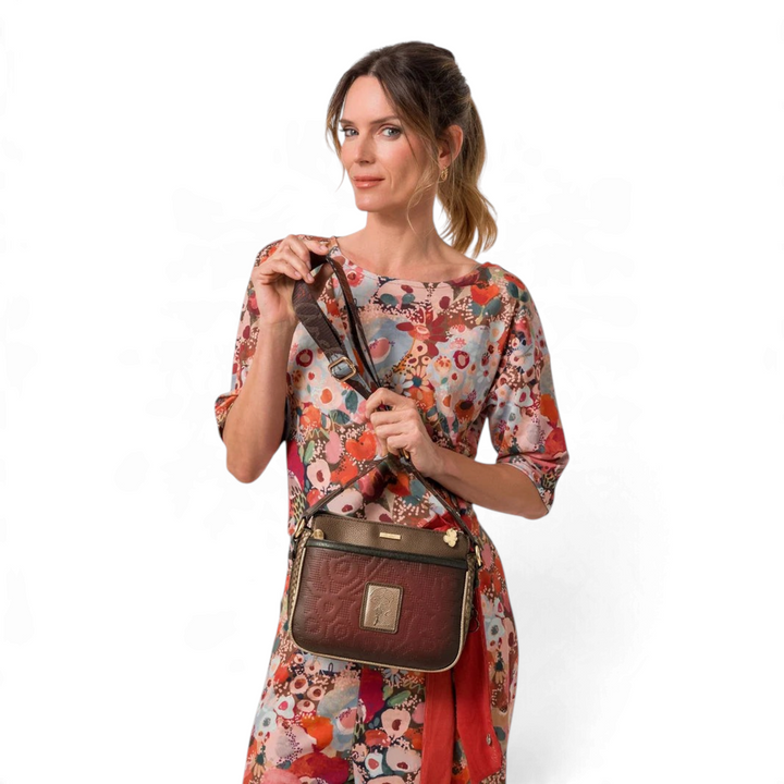 Model wearing an Anekke Core crossbody bag with floral embroidery, metallic details, and a wide jacquard strap.