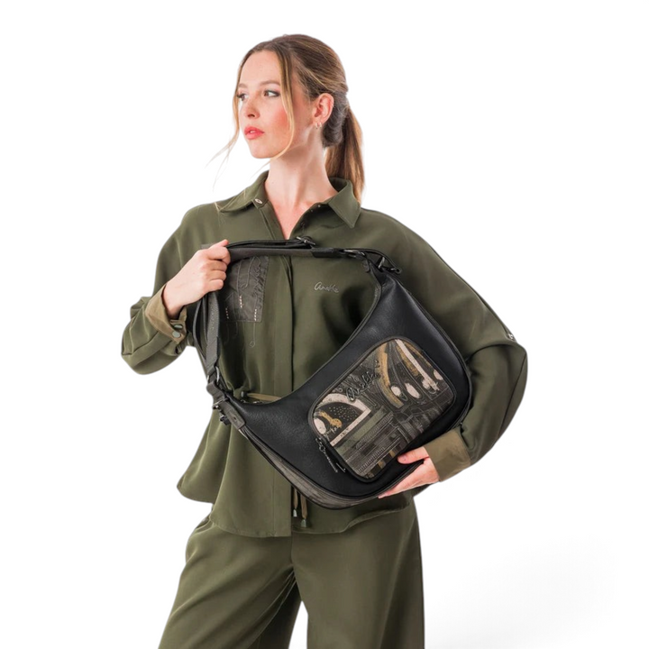 A woman wearing an Anekke hobo shoulder bag in black and grey with artistic metallic details and a wide shoulder strap.